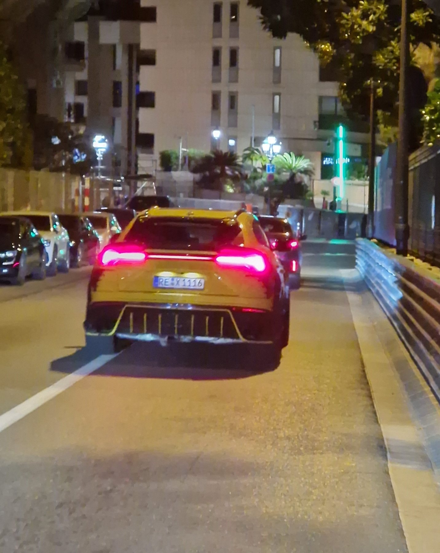A yellow Lamborghini with its tail lights on in a Monte Carlo street at night