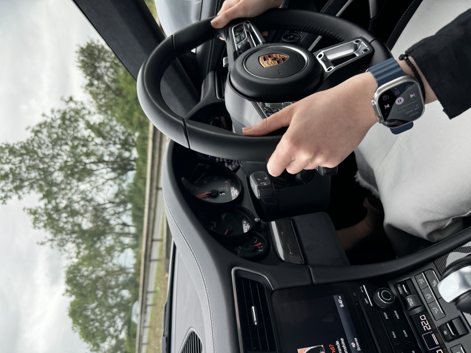 Τα χέρια της συνοδηγού στο τιμόνι της 911, με το Apple Watch στον καρπό