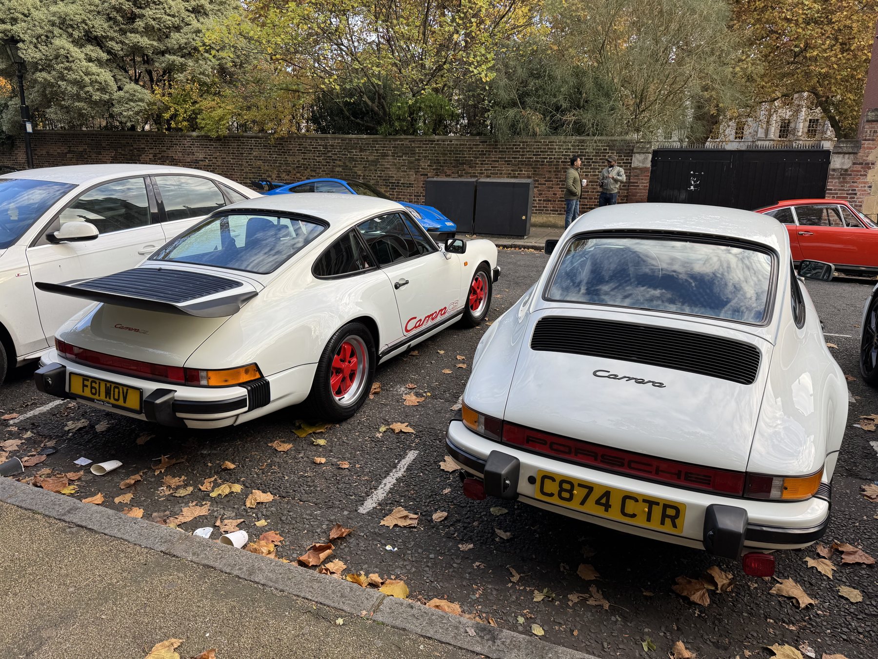 Δύο λευκά Carrera 3.2 της δεκαετίας του '80, το ένα με κόκκινη γραφή Carrera και κόκκινες ζάντες Fuchs