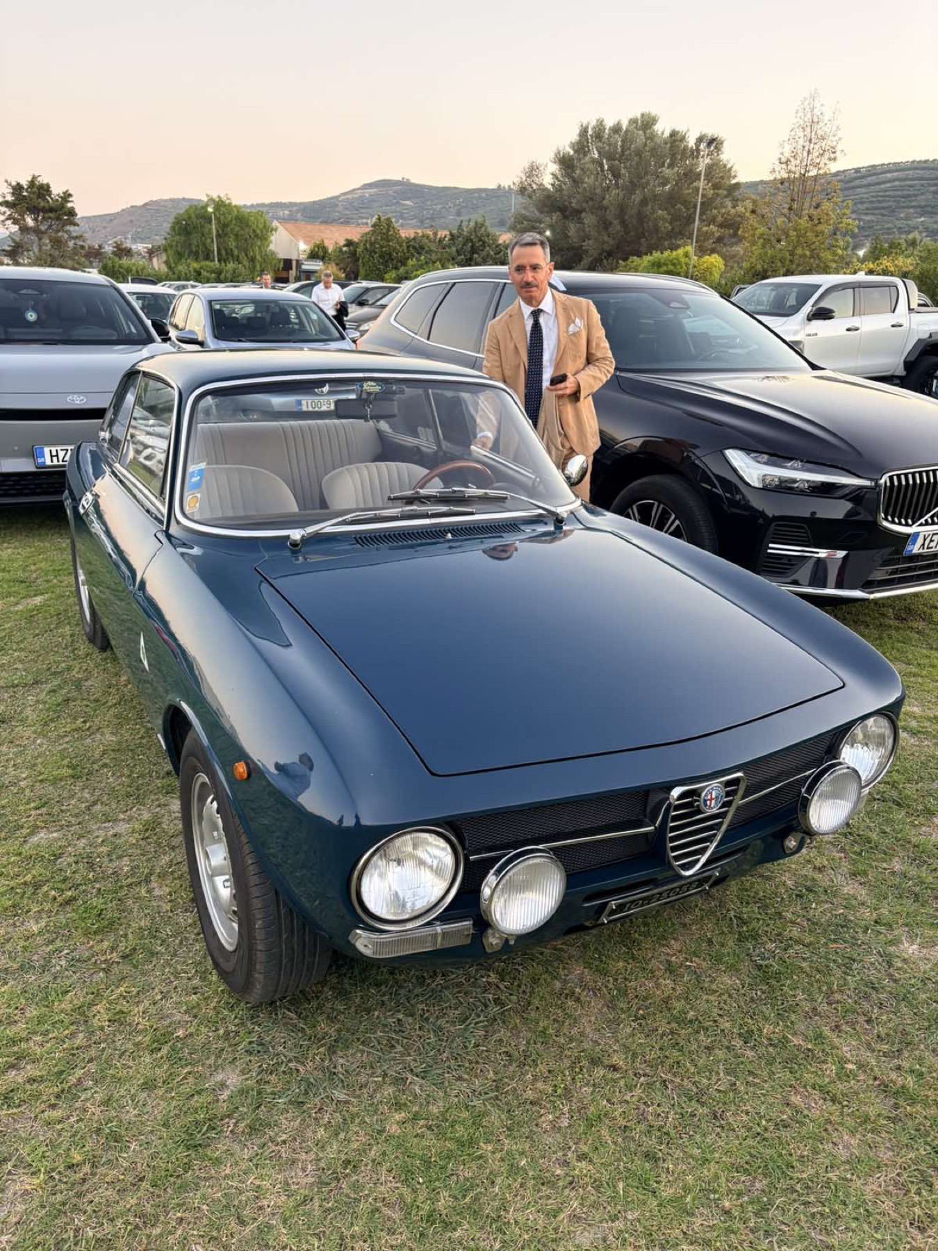 Η μπλε Alfa Bertone παρκαρισμένη σε συνάντηση, με κόσμο γύρω της