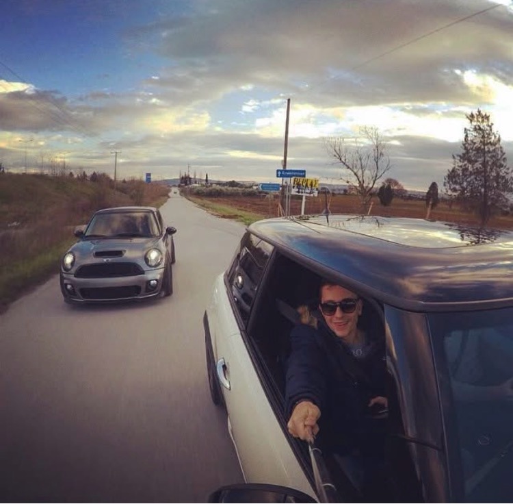 Selfie από το παράθυρο του Mini εν κινήσει, με δεύτερο Mini να ακολουθεί στο ηλιοβασίλεμα