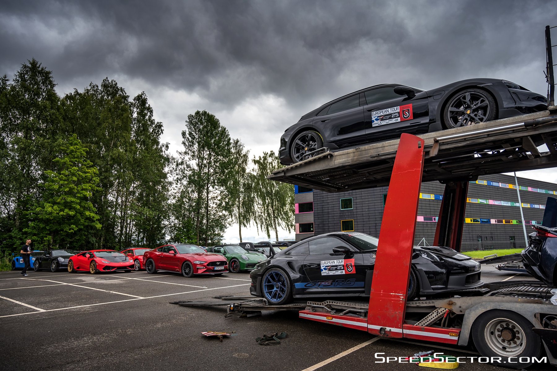 Ανοιχτή αυτοκινητάμαξα με Porsche και Ferrari στα ράφια της, κάτω από βαρύ ουρανό