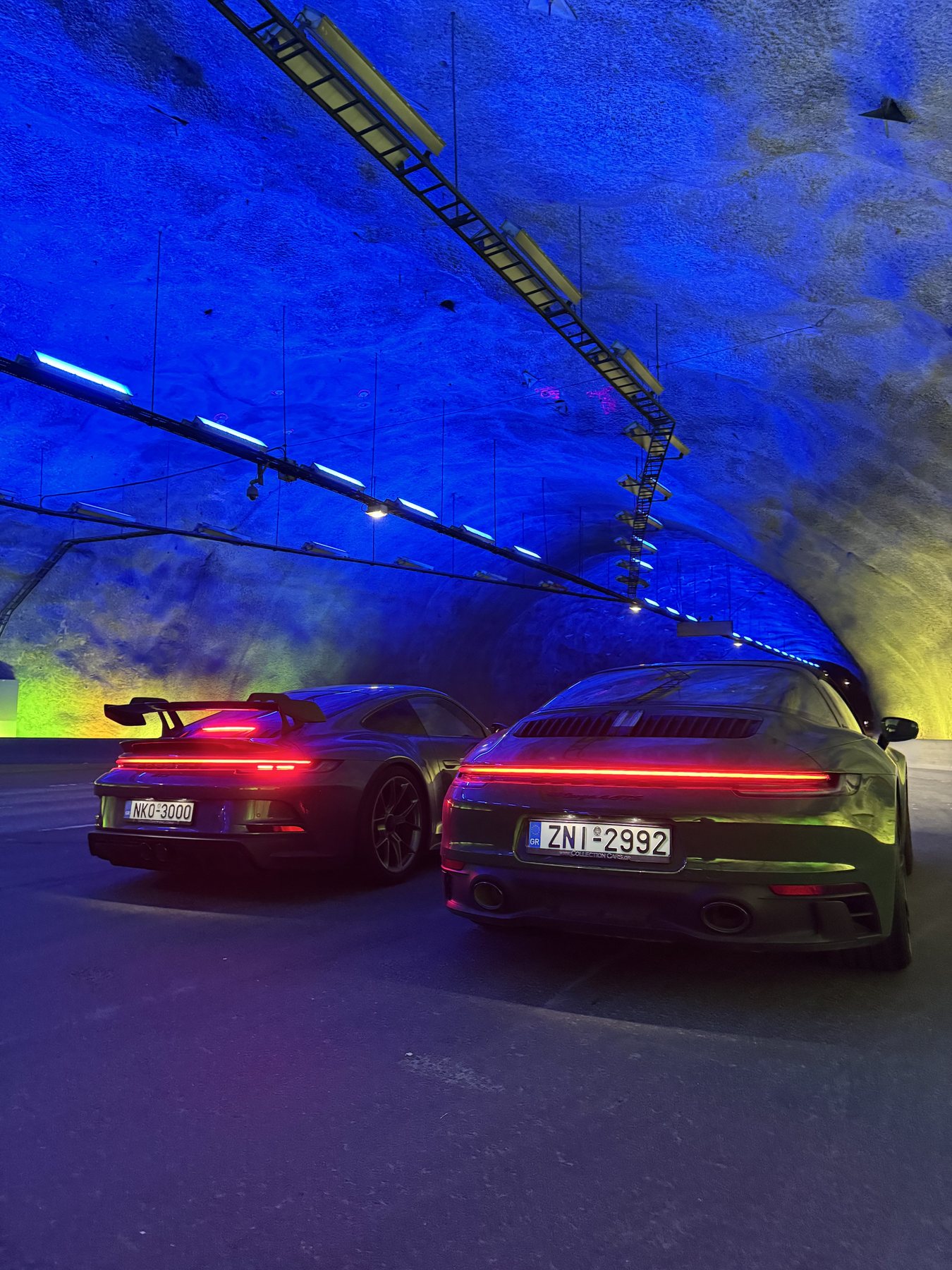 Δύο 911 μέσα στο Lærdal Tunnel, με τα βράχια φωτισμένα σε μπλε χρώμα