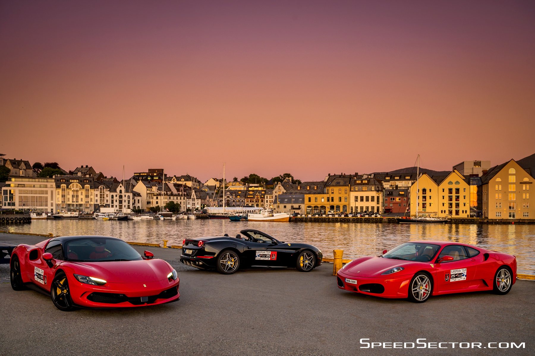 Τρεις κόκκινες Ferrari στο λιμάνι του Ålesund το ηλιοβασίλεμα, με τα χρωματιστά κτίρια της πόλης από πίσω