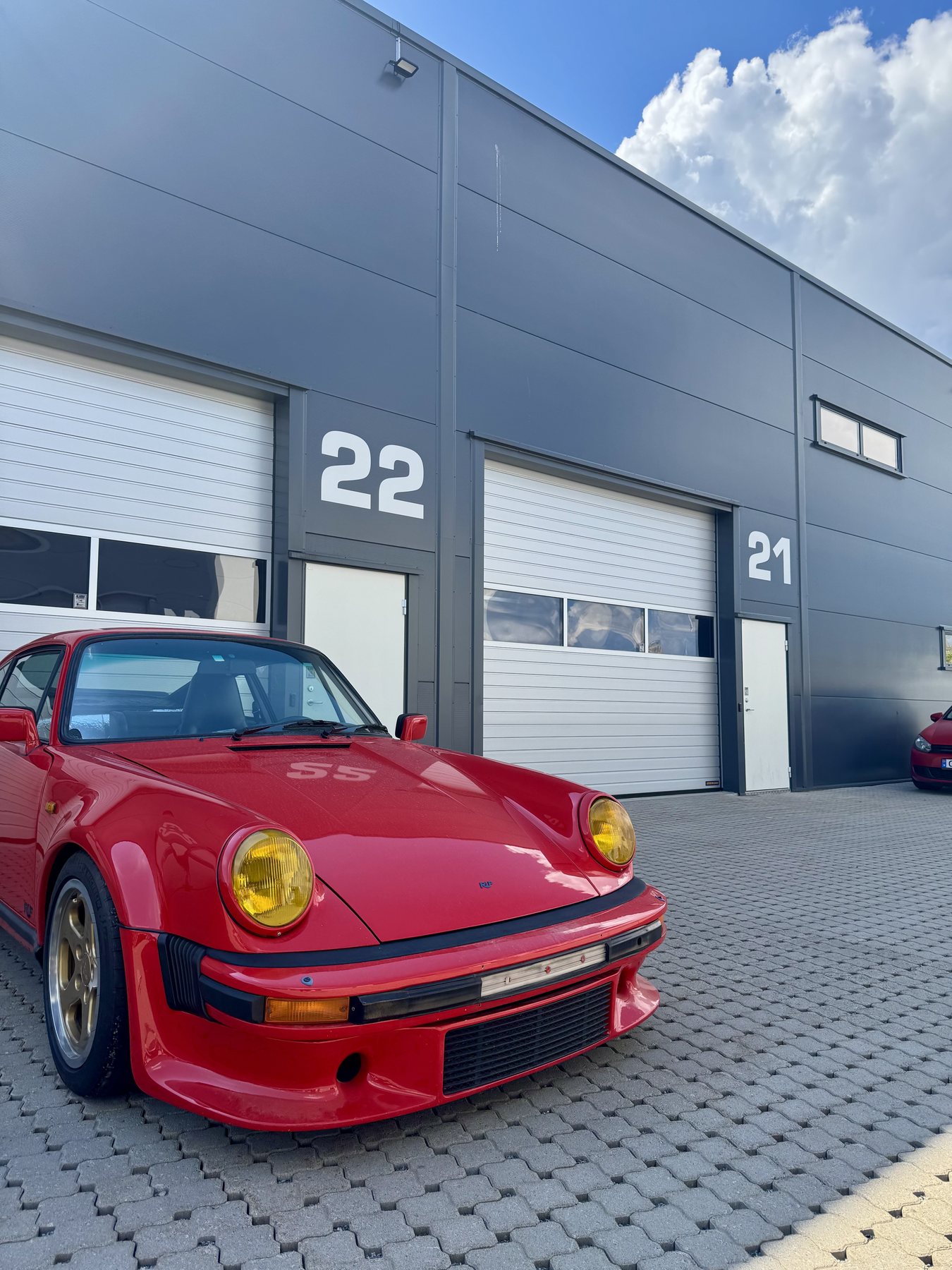 Κόκκινη Porsche 911 964 με φαρδιά φτερά μπροστά στα box της πίστας Rudskogen