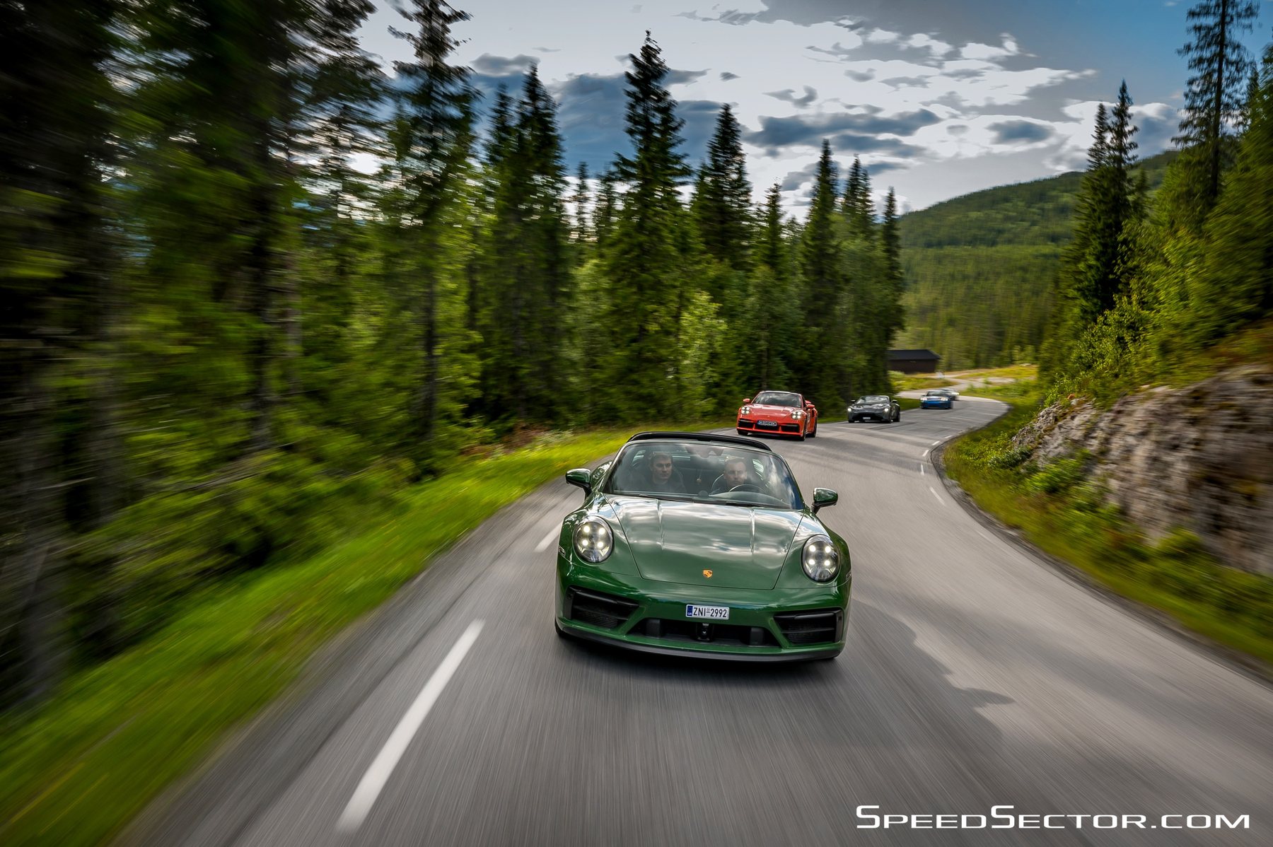 Η πράσινη 911 Targa έρχεται καταπάνω μας σε στροφή, σε δρόμο μέσα σε δάσος, με άλλα αυτοκίνητα να ακολουθούν