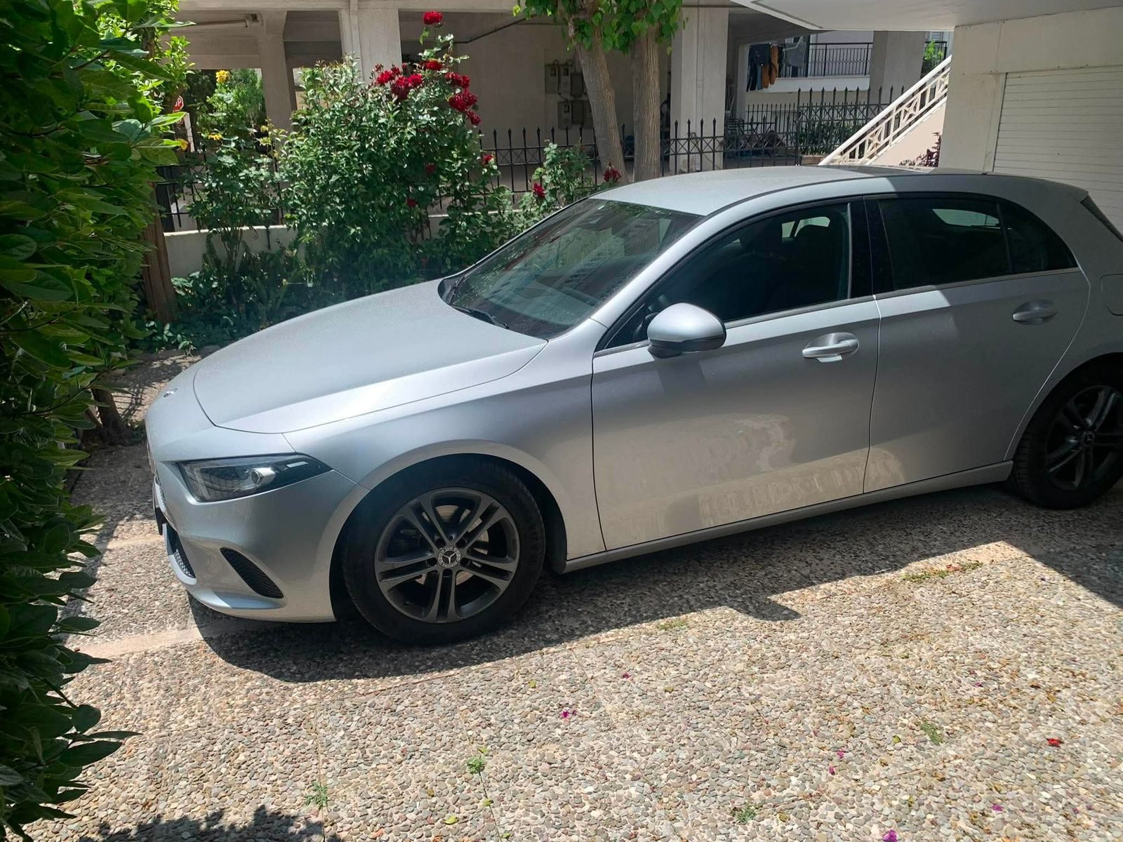 Ασημί Mercedes A-Class παρκαρισμένη σε αυλή με τριανταφυλλιές