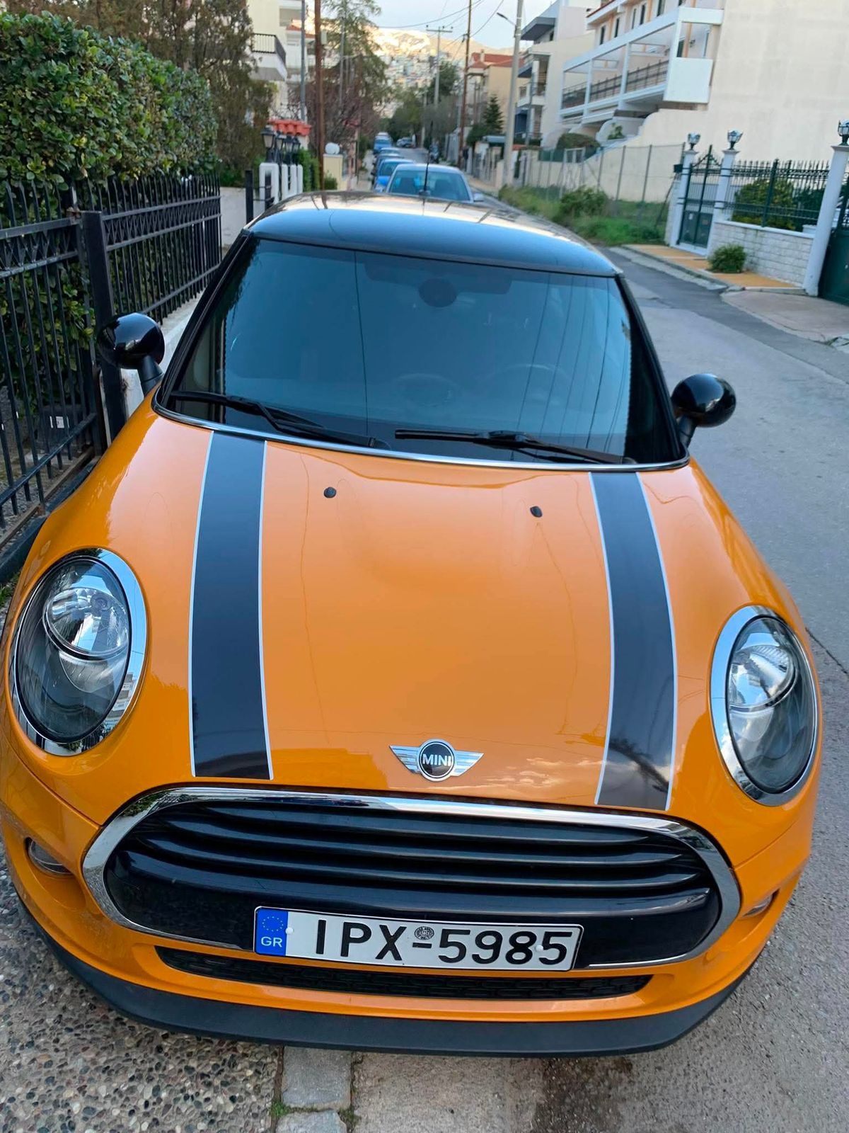 Πορτοκαλί Mini Cooper με μαύρες ρίγες, παρκαρισμένο στον δρόμο