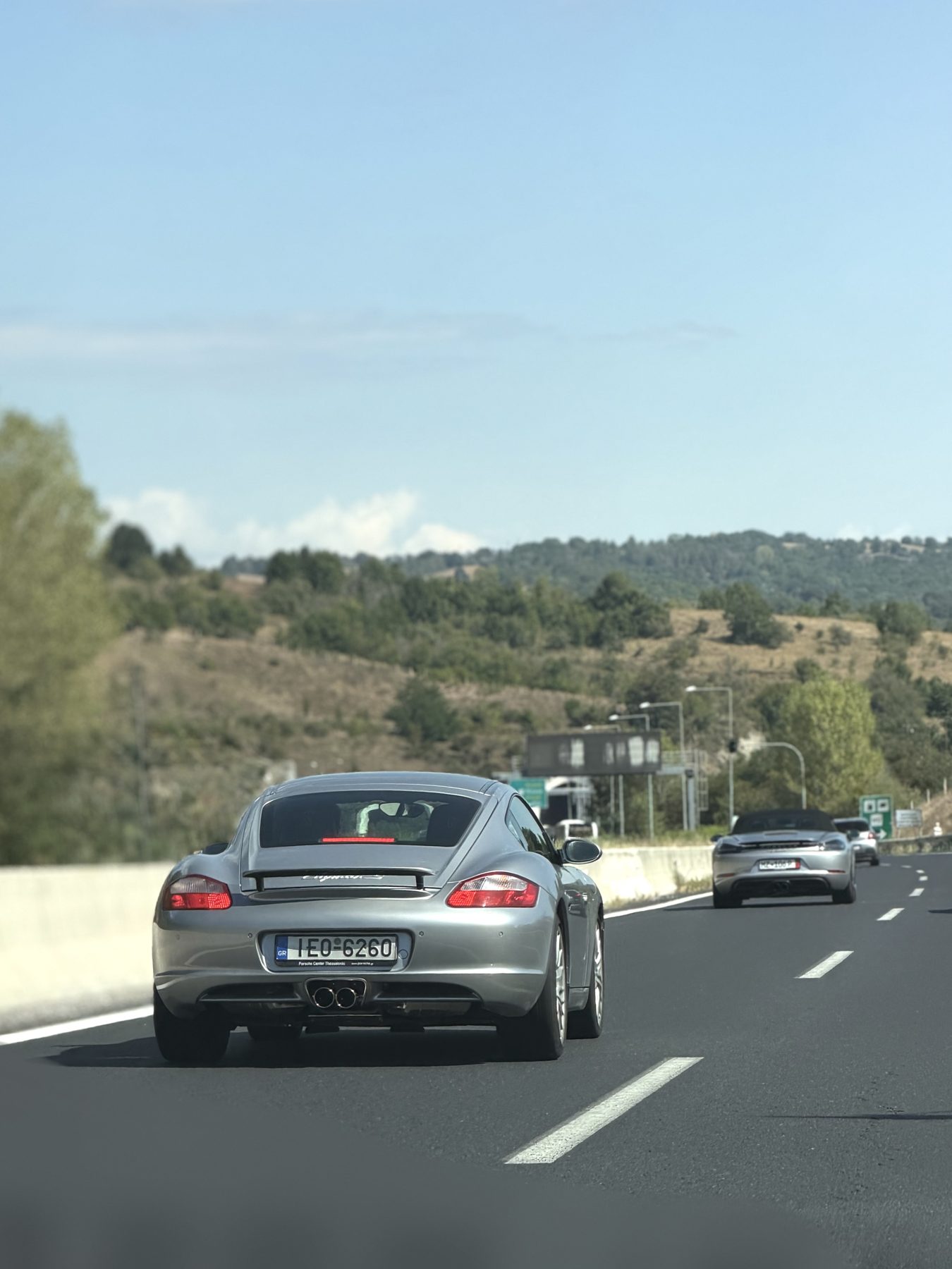 Η Cayman S και το Boxster στον αυτοκινητόδρομο, με λόφους στο βάθος