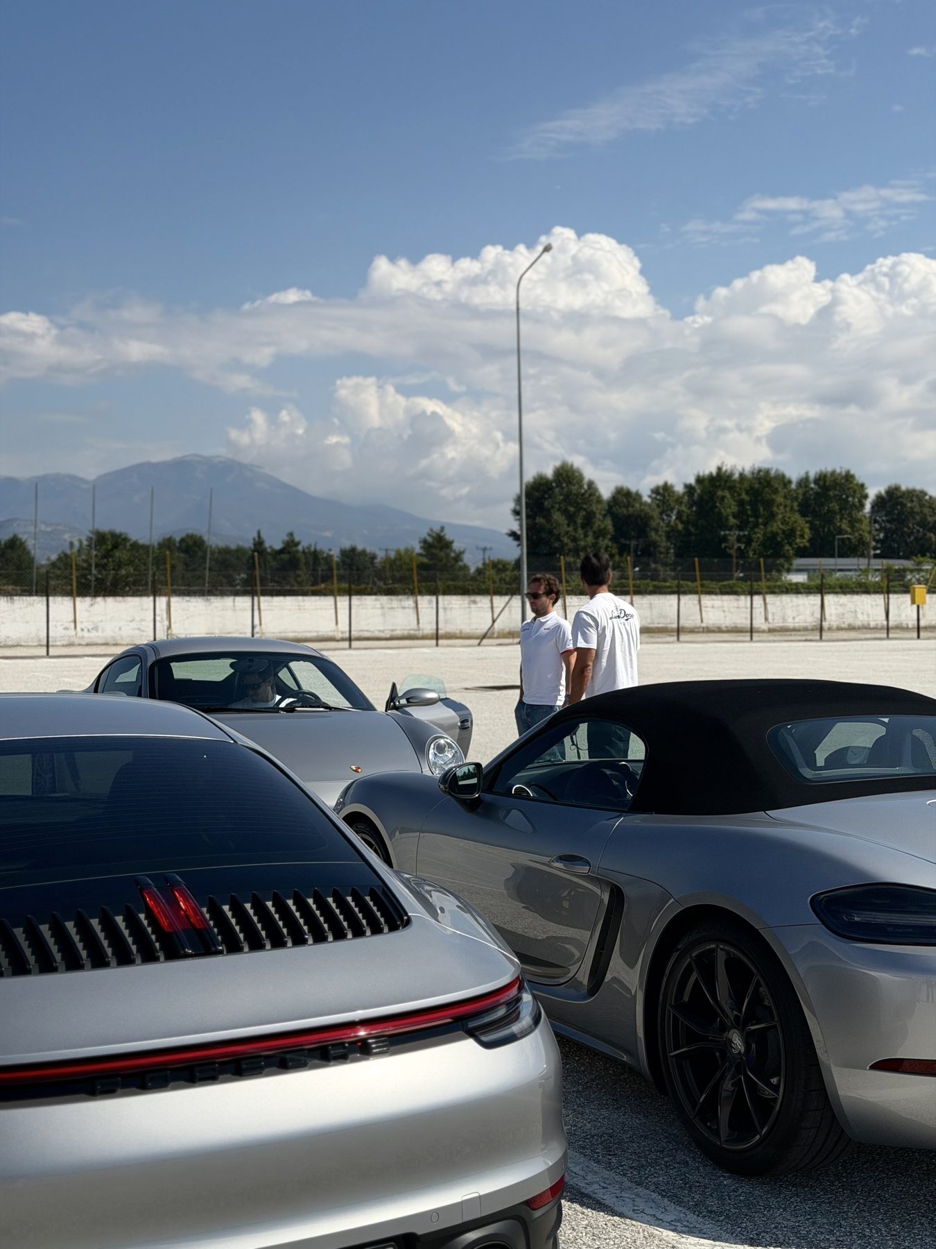 Το 992 Carrera και το 718 Boxster T παρκαρισμένα στο paddock, με δύο από την παρέα να συζητούν δίπλα τους