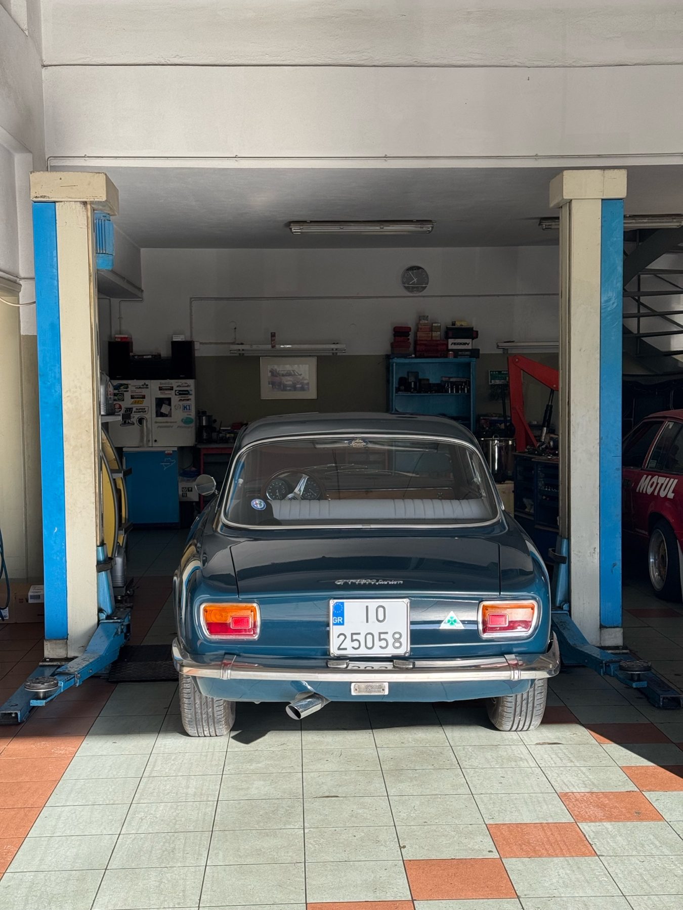 Η Alfa Romeo Junior από πίσω, ψηλά στο αναβατόριο ανάμεσα στις δύο μπλε κολόνες του συνεργείου