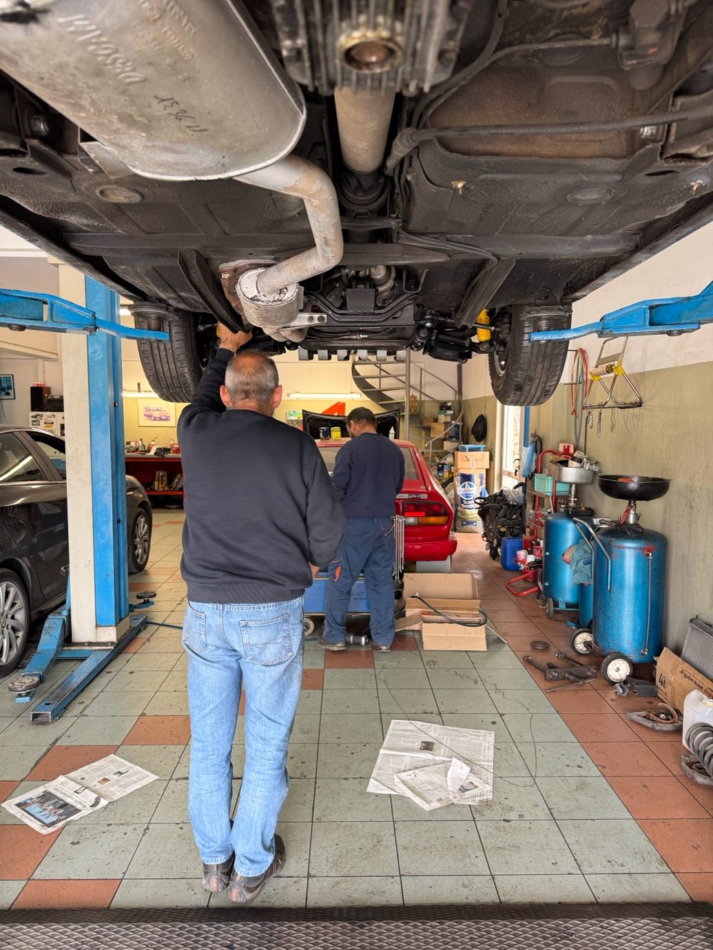 Η Alfa Romeo από κάτω, με την εξάτμιση σε πρώτο πλάνο και τον μηχανικό να στέκεται από κάτω της