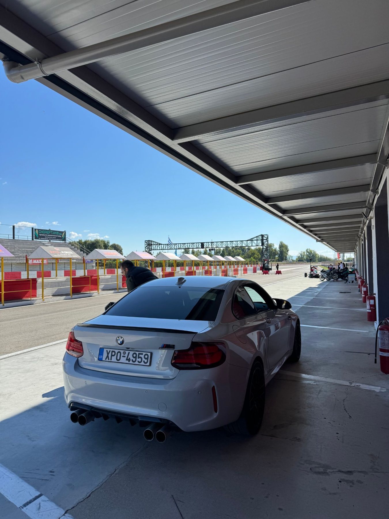 Η ασημί BMW M2 Competition από πίσω, κάτω από το στέγαστρο των pits, με την ευθεία της πίστας των Σερρών μπροστά της